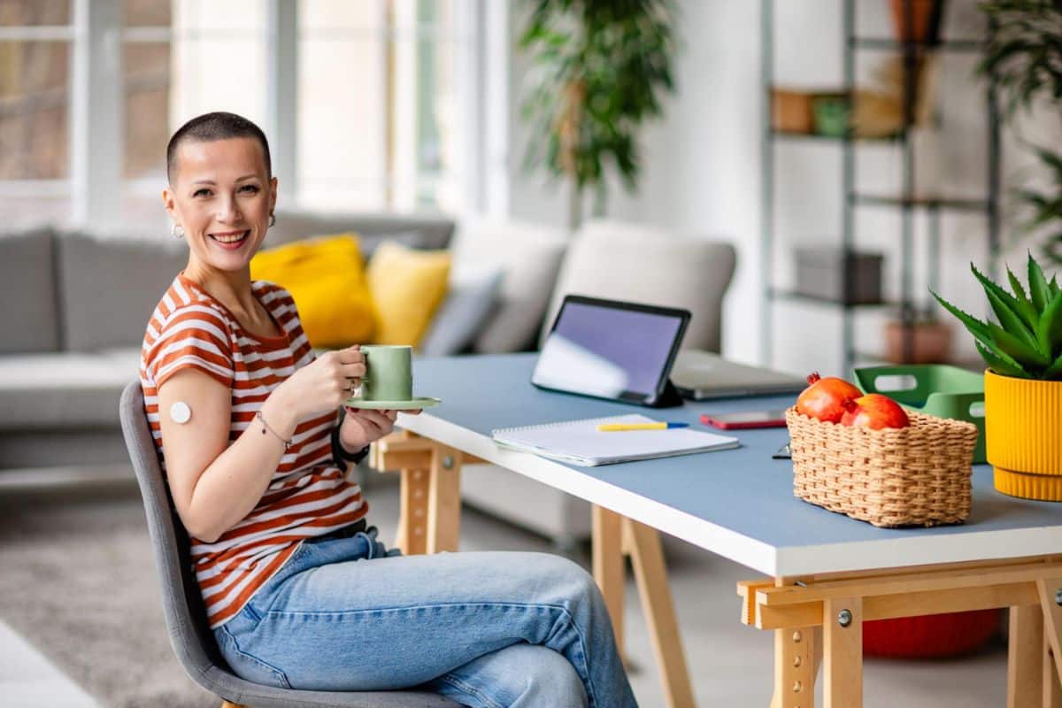 Smiling woman living with Type 1 diabetes holding a mug while managing her health with confidence.